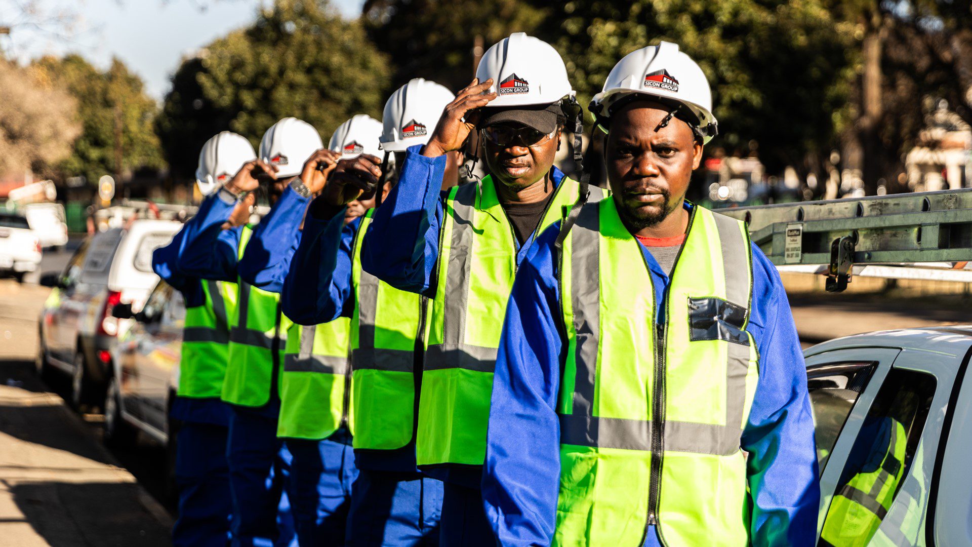 Workers in high vis vests lined up for roofing repairs