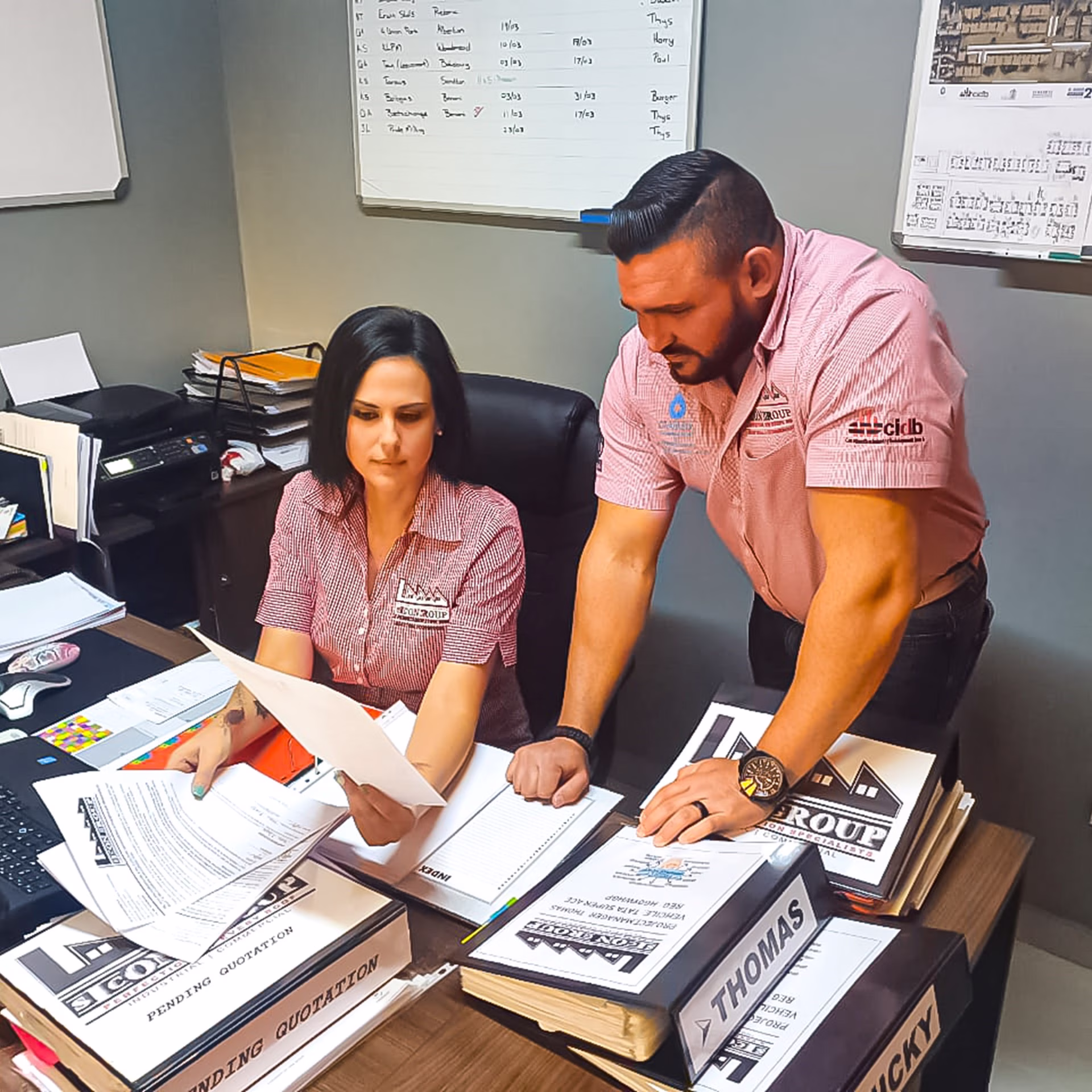 Male and female staff discussing paperwork and plans in a Sicon Group office setting