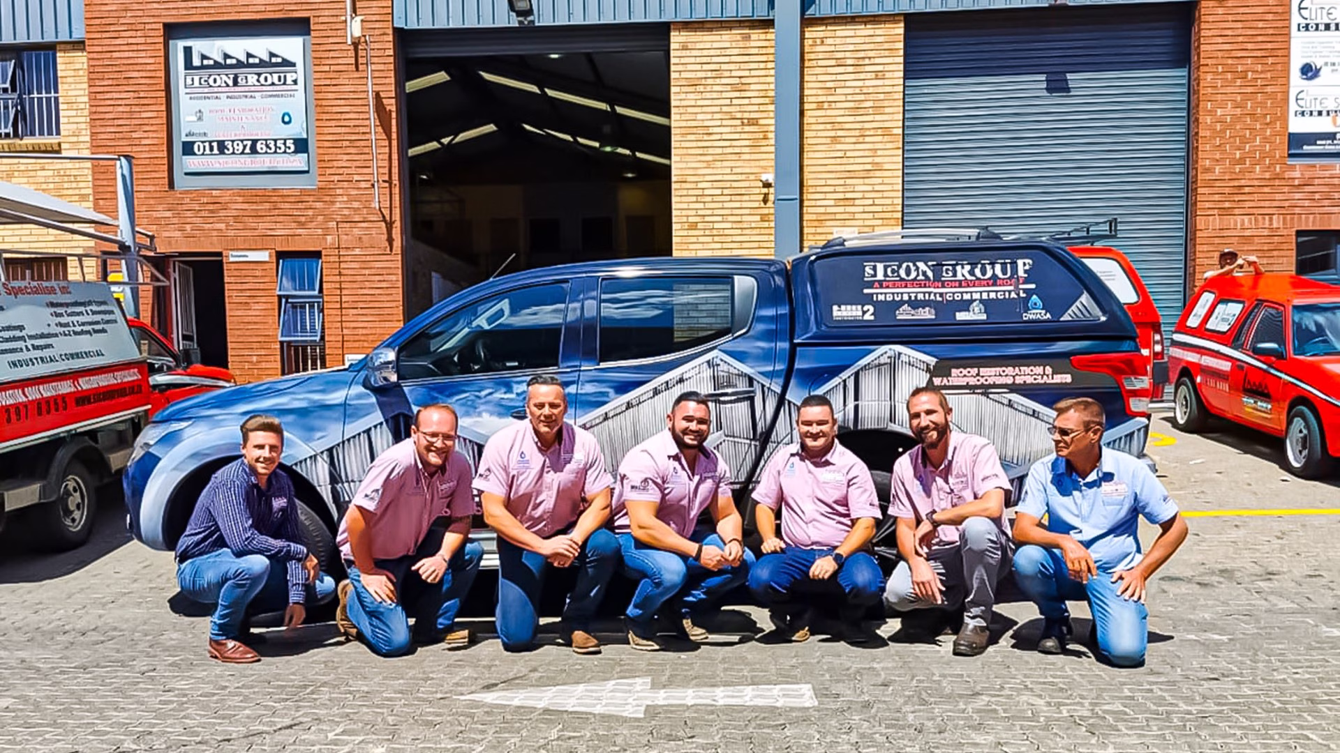 Sicon team members in branded shirts gathered outside the main warehouse with red vehicles