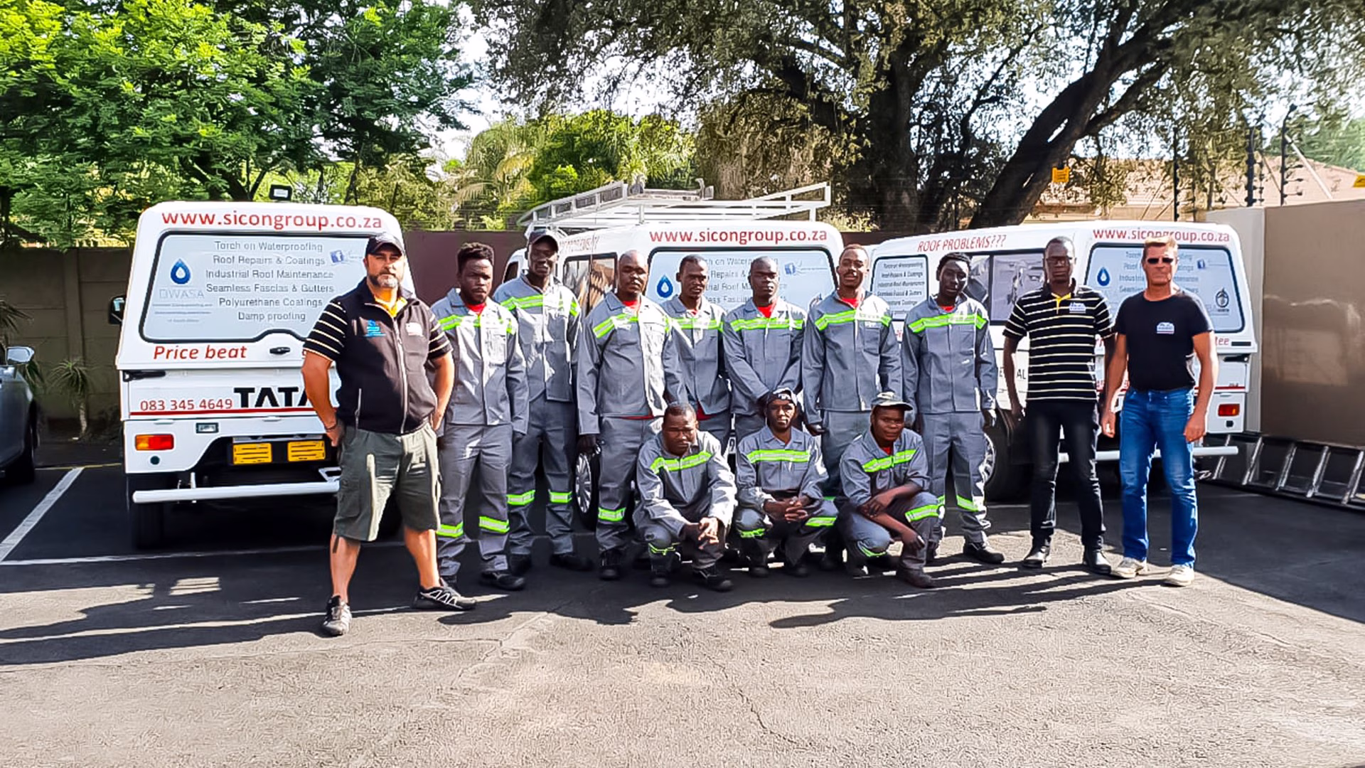 Group of Sicon Group staff standing beside branded vehicles in uniform outside the premises