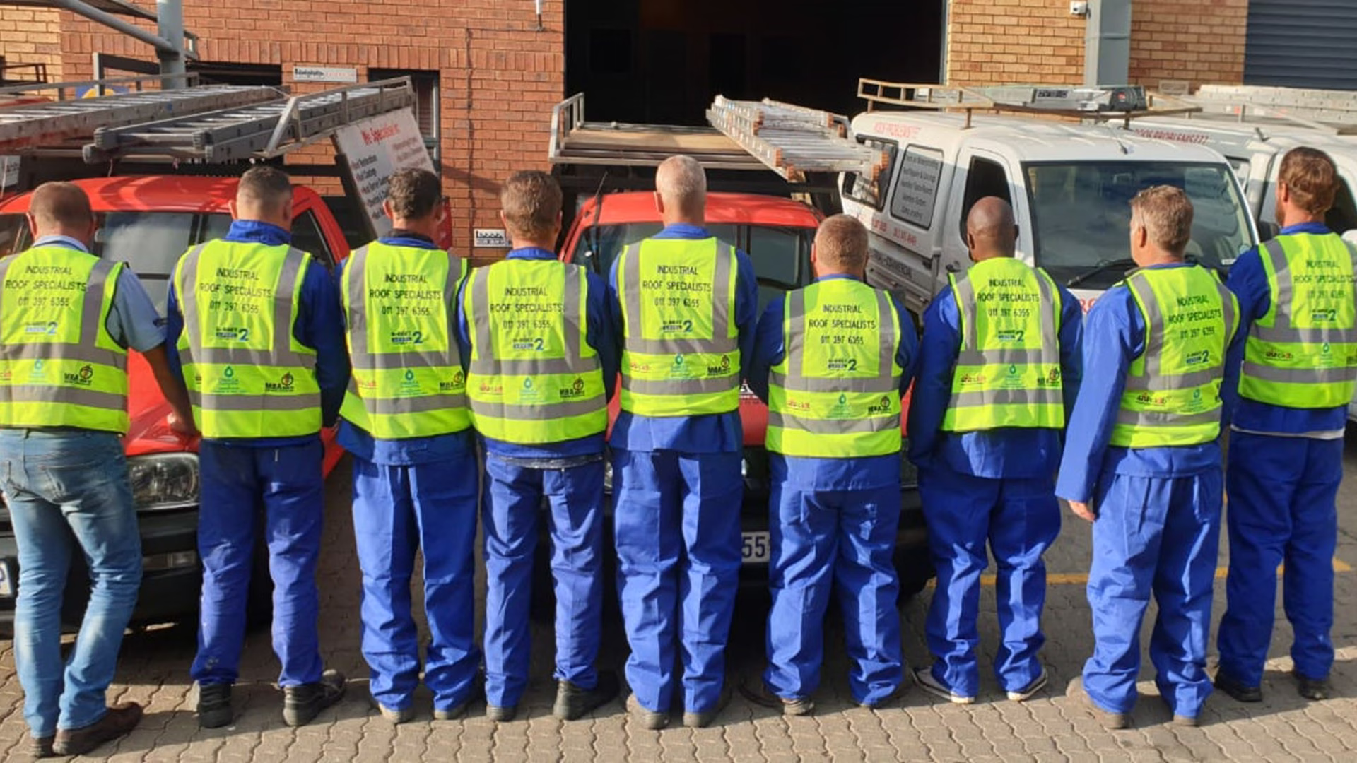 Back view of Sicon crew in green reflective vests standing in a line at an industrial site